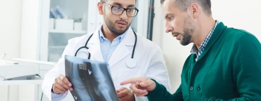 Doctor and patient pointing at x-ray image of joint during medical consultation